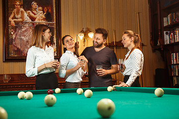 Image showing Young men and women playing billiards at office after work.