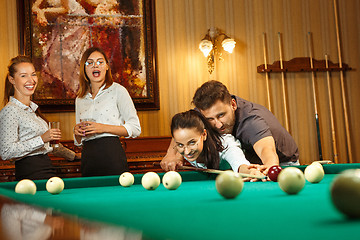 Image showing Young men and women playing billiards at office after work.