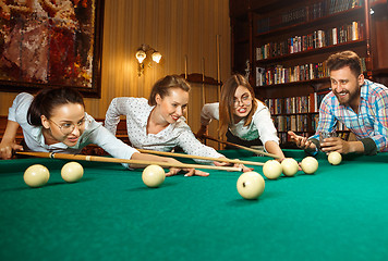 Image showing Young men and women playing billiards at office after work.