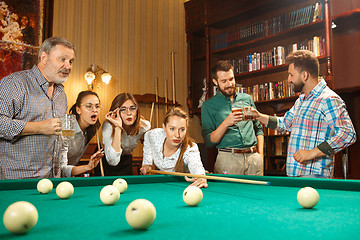 Image showing Young men and women playing billiards at office after work.