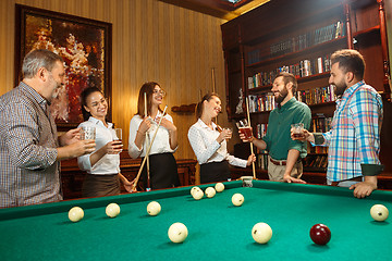 Image showing Young men and women playing billiards at office after work.