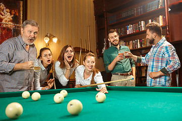 Image showing Young men and women playing billiards at office after work.