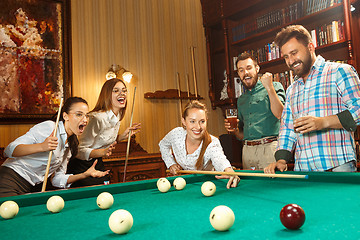 Image showing Young men and women playing billiards at office after work.