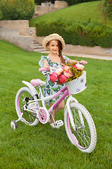 Image showing Beautiful little girl riding a bicycle through the park. Nature, lifestyle