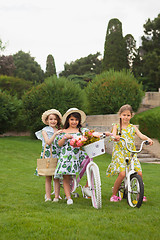 Image showing Beautiful little girls riding a bicycle through the park. Nature, lifestyle