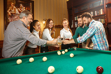 Image showing Young men and women playing billiards at office after work.