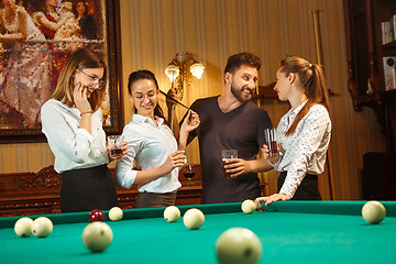 Image showing Young men and women playing billiards at office after work.