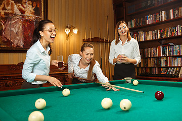 Image showing Young women playing billiards at office after work.