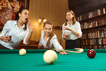 Image showing Young women playing billiards at office after work.