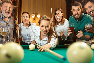 Image showing Young men and women playing billiards at office after work.