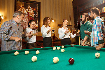 Image showing Young men and women playing billiards at office after work.