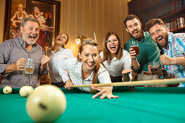 Image showing Young men and women playing billiards at office after work.