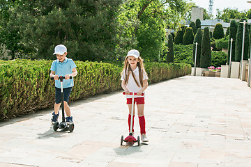 Image showing Preschooler girl and boy riding scooter outdoors.