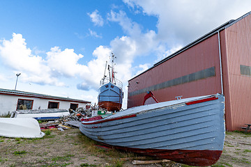 Image showing Wooden boat on land with a large ship