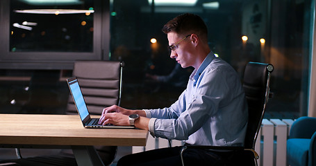 Image showing man working on laptop in dark office