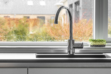 Image showing Chrome faucet by a kitchen sink with a wet window
