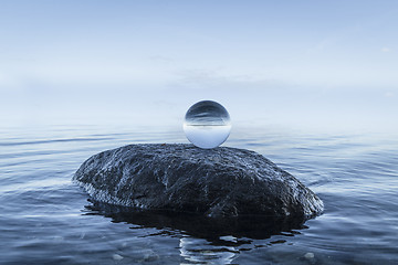 Image showing Crystal orb on a black rock by the blue ocean