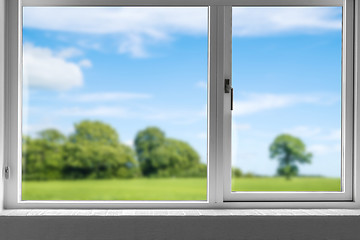 Image showing View from a closed window to a green meadow