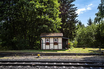 Image showing Small house close to a railroad with red flowers