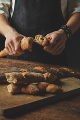 Image showing Male hands break the baguette