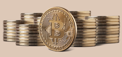 Image showing Single bitcoin coin standing in front of stacks of coins