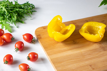 Image showing Vegetables for salad.Cherry tomatoes, yellow pepper, arugula, on a white kitchen table.