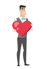 Image showing Caucasian groom holding a big red heart.