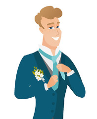 Image showing Young caucasian cheerful groom adjusting tie.