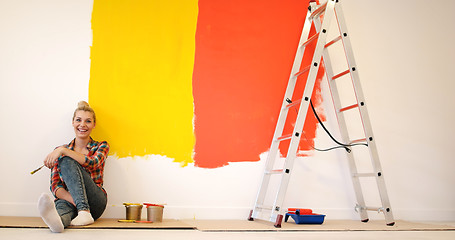 Image showing young female painter sitting on floor