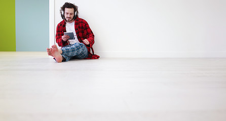 Image showing young man listenig music on tablet at home