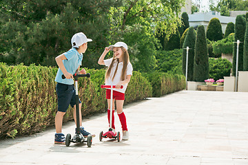 Image showing Preschooler girl and boy riding scooter outdoors.