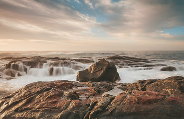 Image showing Sunlight hitting the rocks with ocean waterfall cascades