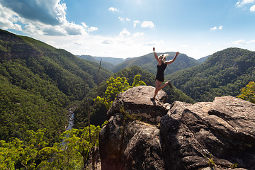 Image showing Spirited woman jumping on a high cliff ledge.