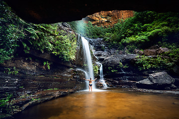 Image showing Woman cooling off in a mountain oasis and waterfall