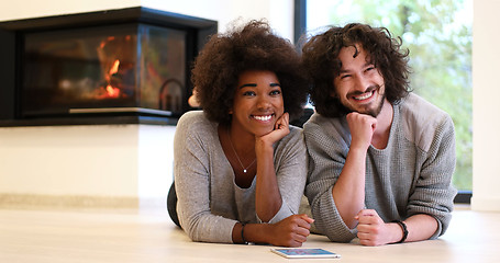 Image showing multiethnic couple lying on the floor  in front of fireplace