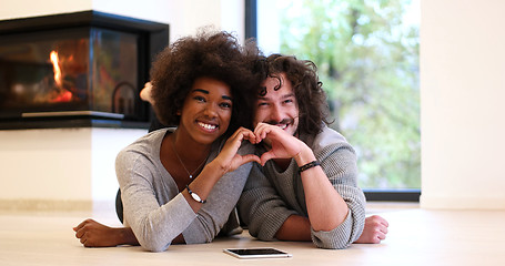 Image showing multiethnic couple showing a heart with their hands on the floor