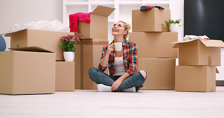 Image showing woman with many cardboard boxes sitting on floor