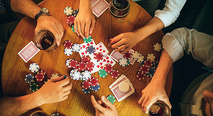 Image showing Top view photo of friends sitting at wooden table. Friends having fun while playing board game.