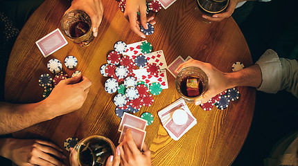 Image showing Top view photo of friends sitting at wooden table. Friends having fun while playing board game.