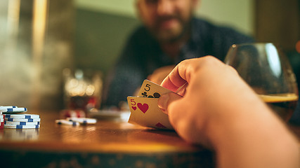 Image showing Side view photo of friends sitting at wooden table. Friends having fun while playing board game.