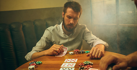 Image showing Side view photo of friends sitting at wooden table. Friends having fun while playing board game.