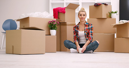 Image showing woman with many cardboard boxes sitting on floor