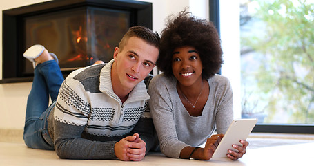 Image showing multiethnic couple using tablet computer on the floor