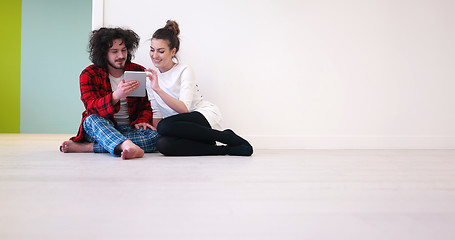 Image showing Young Couple using digital tablet on the floor