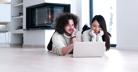 Image showing young multiethnic couple using a laptop on the floor