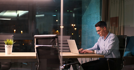 Image showing man working on laptop in dark office