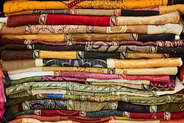 Image showing Pile of colorful folded textile. Heap of cloth fabric