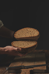 Image showing man baker holds in his hands halves of rye bread,