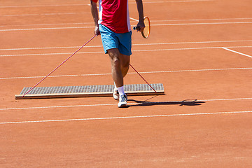 Image showing Player aligns surface tennis court, with pulling network