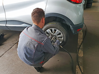 Image showing Worker changes the car's tire